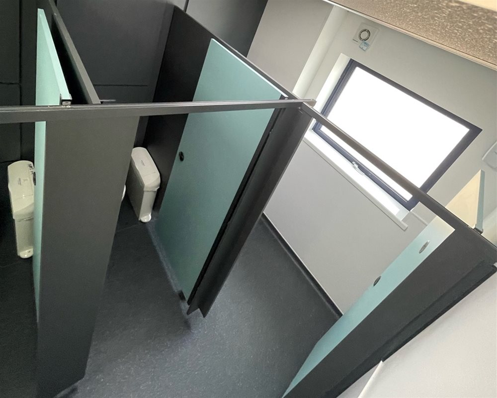 Dark grey duct panels and flashgaps, Dark Grey standard height modular toilet cubicles with Mint Green doors and Dark Grey fittings.